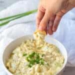 a hand dipping a cheese crisp into keto egg salad to show the texture