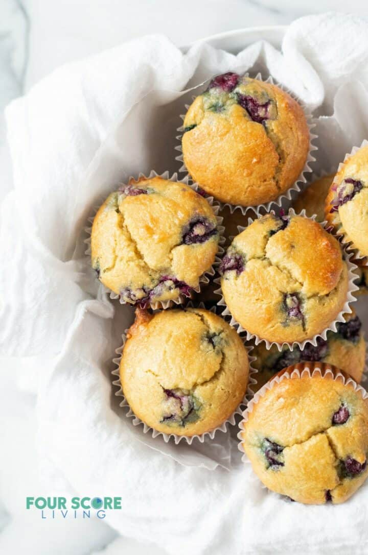 almond flour blueberry muffins in a white bowl with a white tea towel
