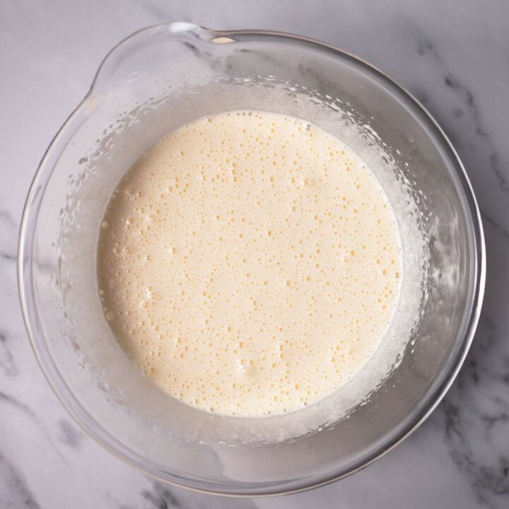 Glass bowl with whisked eggs, sugar, oil and butter.