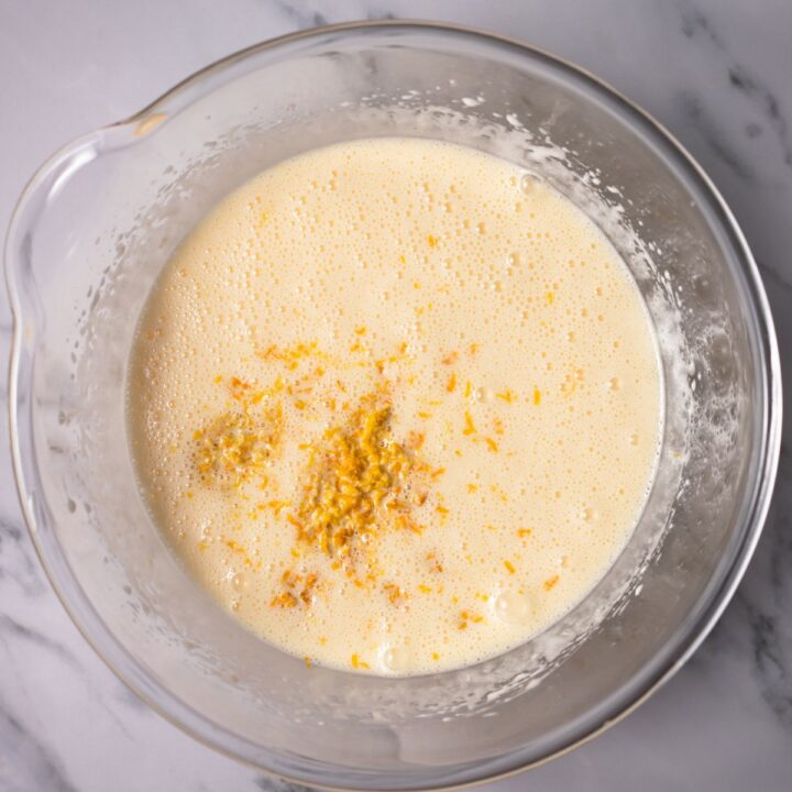 Mixed wet cake ingredients with orange zest being added.