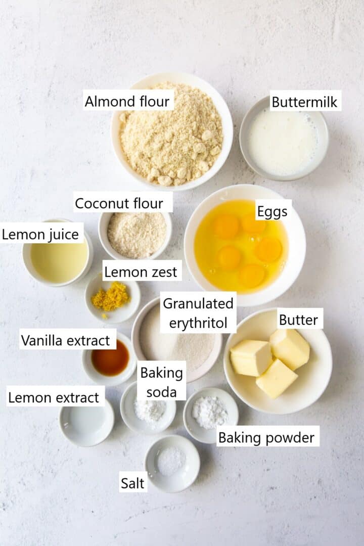 Ingredients for keto lemon cake in individual bowls, including butter, eggs, flours, lemon zest, and others.