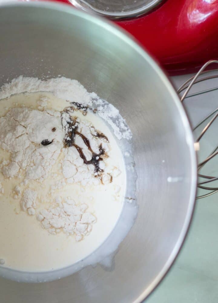Stand mixer bowl with heavy cream, sugar free sweetener and vanilla extract, unmixed.