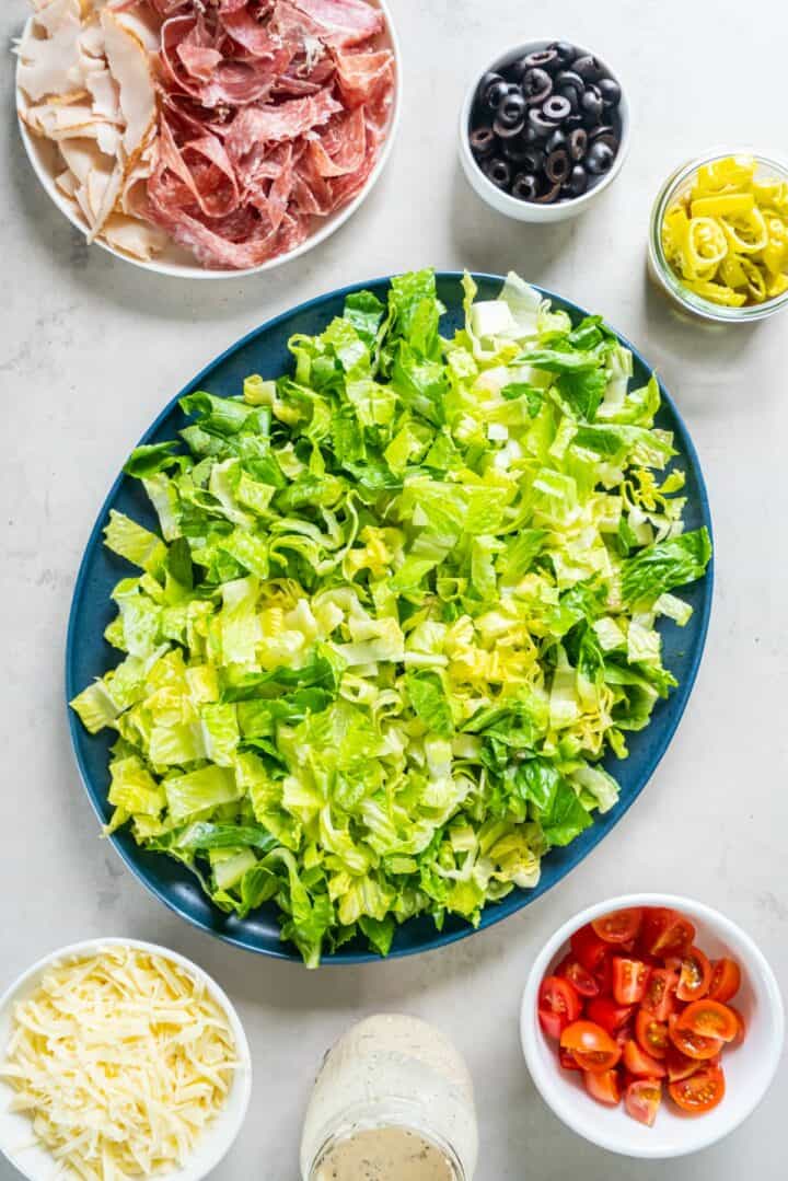 A plate of romaine lettuce surrounded by remaining salad ingredients.