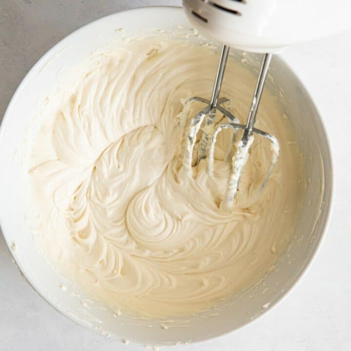 Bowl with smooth cream cheese filling mixed by a hand mixer.