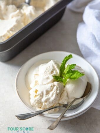 a bowl of vanilla ice cream with mint garnish and two spoons.