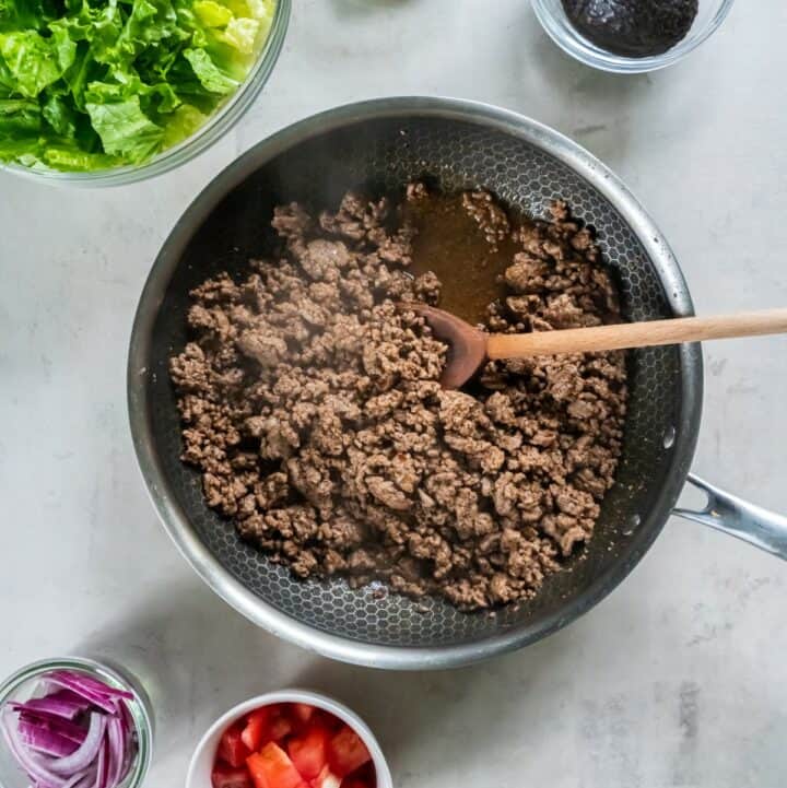 Skillet with fully cooked ground beef that is being allowed to cool before making the salad.