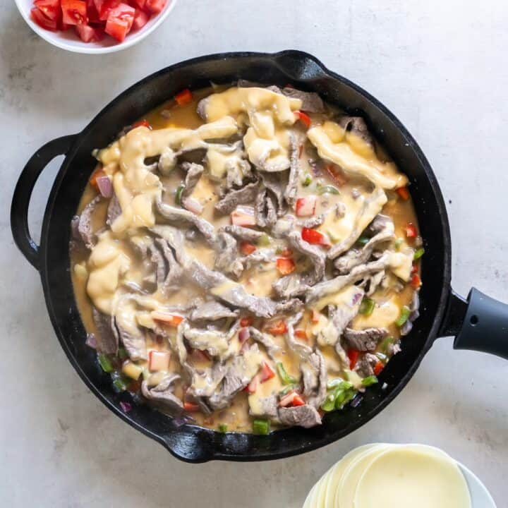 Cast iron skillet with melted cheddar cheese mixed into the beef and veggies.