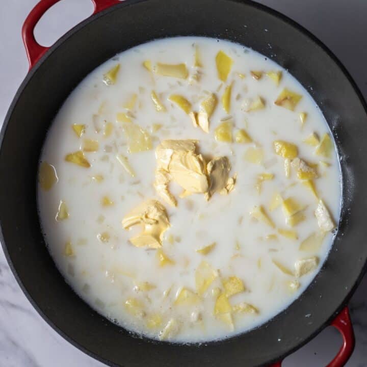 Milk and butter added to the cooked potatoes in a stock pot.