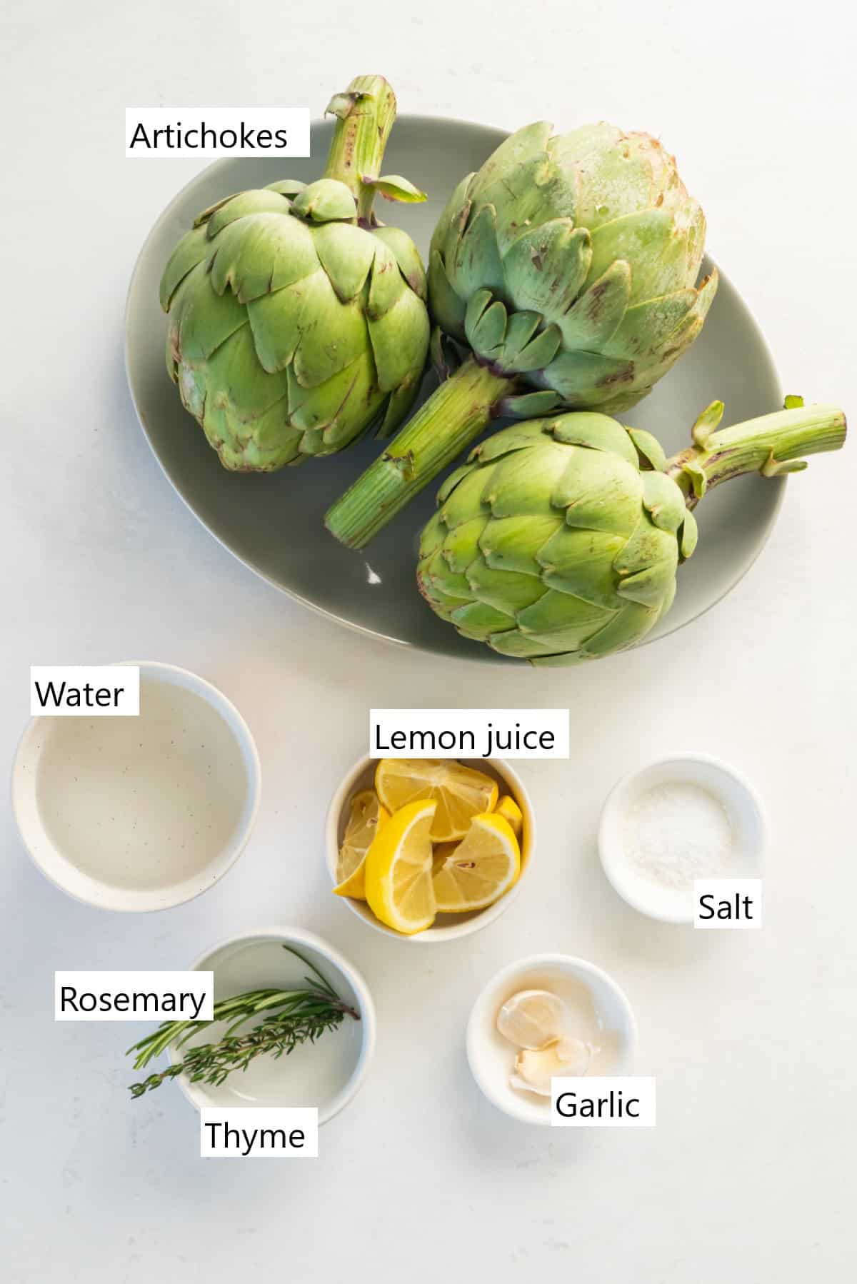 The ingredients needed to make instant pot artichokes, including three artichokes, lemon, garlic, and seasonings.