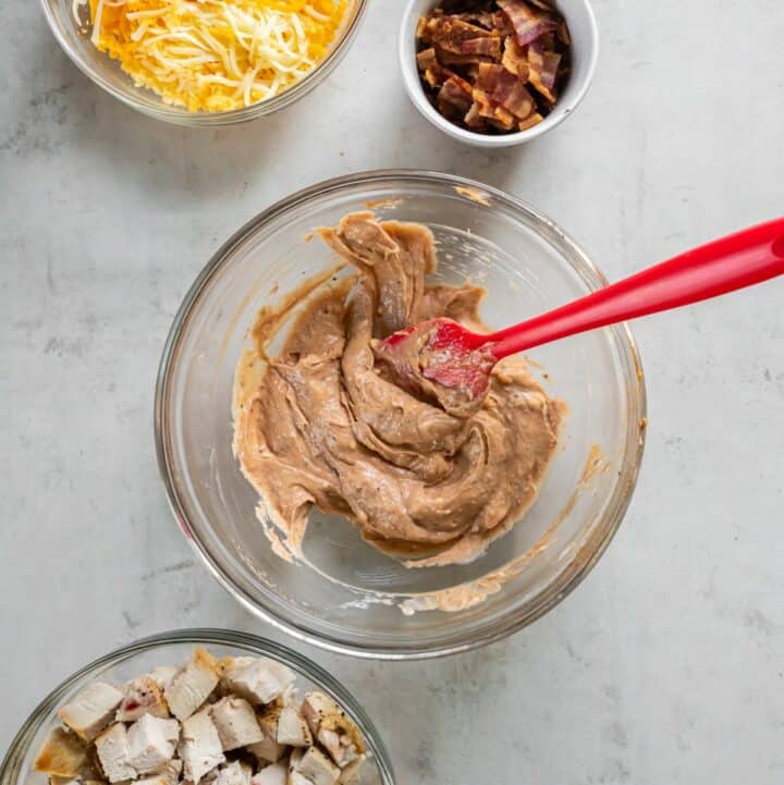 Glass bowl with cream cheese, BBQ sauce, ranch seasoning mixture being combined.