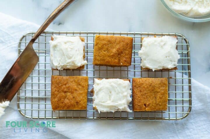 6 keto pumpkin bars on a wire rack. 3 with frosting and 3 without.