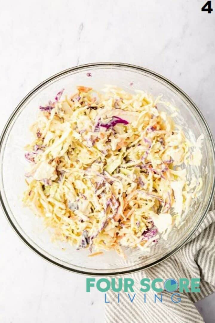 Finished coleslaw in a glass bowl.