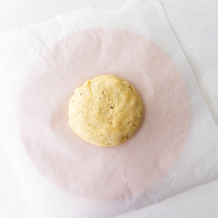 Kneaded ball of fathead pizza dough on parchment paper.