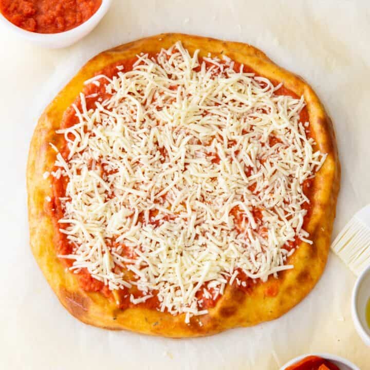 Pizza crust with pizza sauce and then topped with shredded mozzarella cheese.