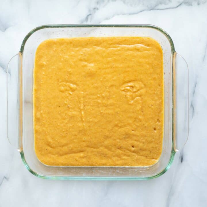 The pumpkin bars batter poured into a glass 8 by 8 baking dish.