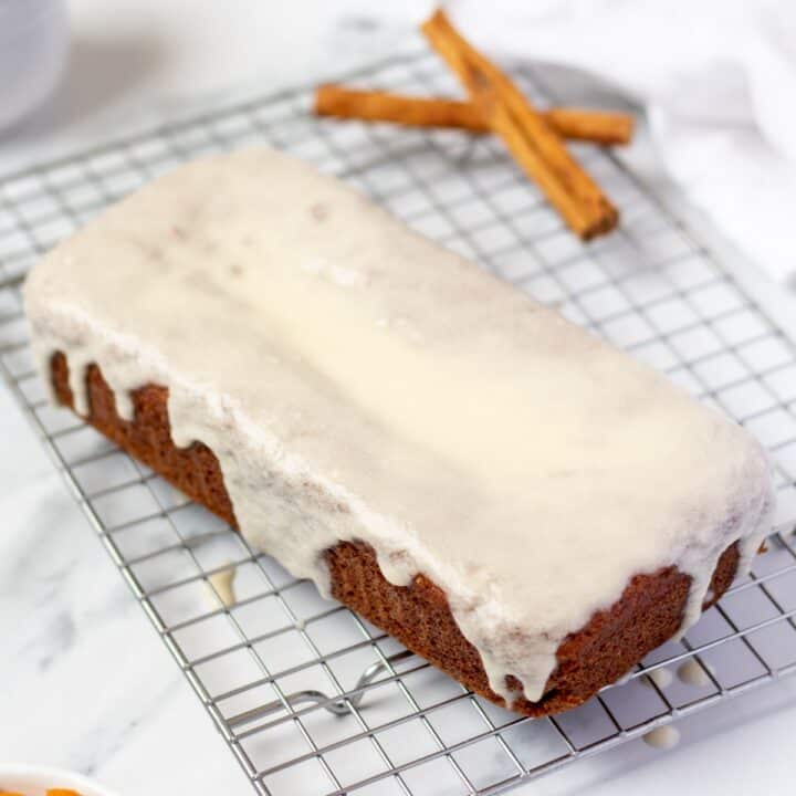 Baked keto pumpkin bread topped with icing on a wire rack.