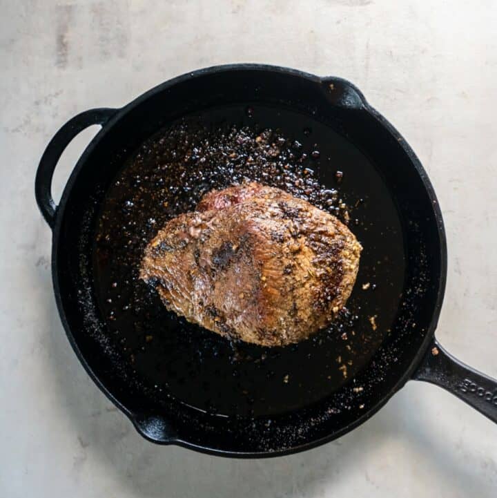 Fully cooked sirloin tip roast in a large iron skillet.