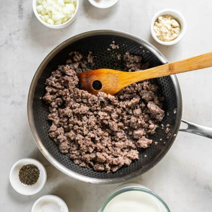 Frying pan with crumbled ground sausage being cooked.