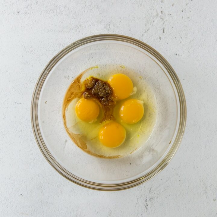 Glass bowl with unmixed eggs, lemon erythritol mixture, lemon zest, stevia and vanilla.