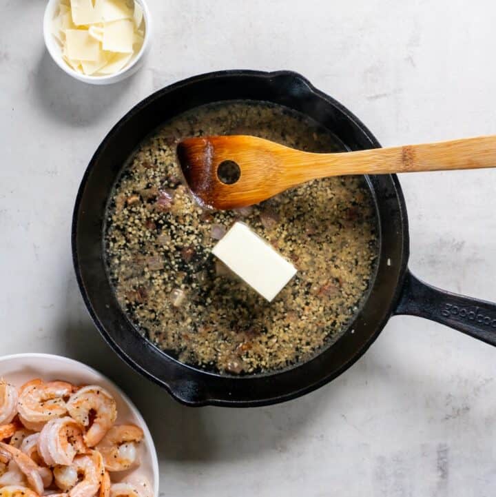 Butter being added to white wine, garlic and onions.