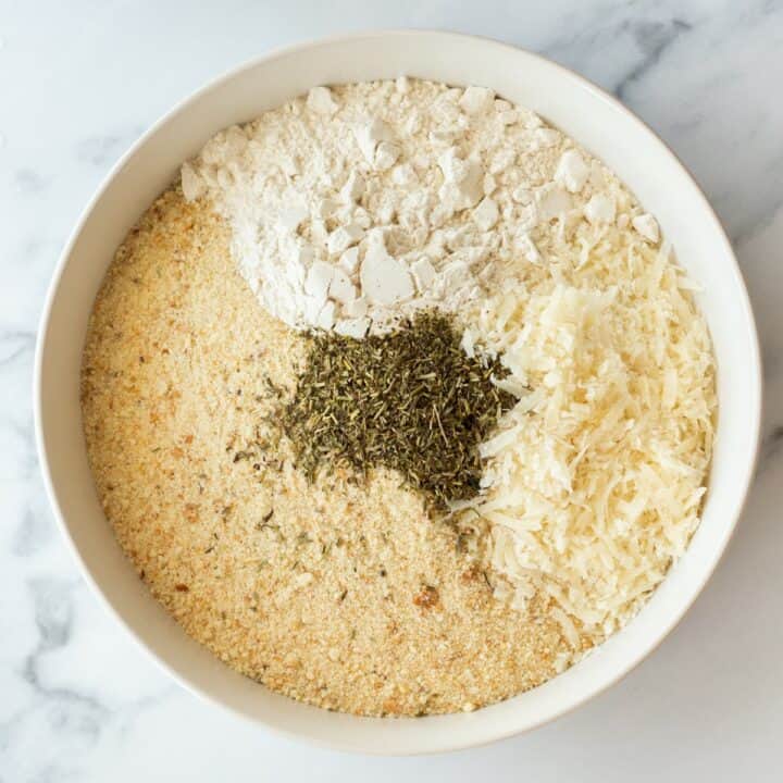 Bowl with breadcrumbs, flour, parmesan cheese and Italian seasoning for dredging the chicken.