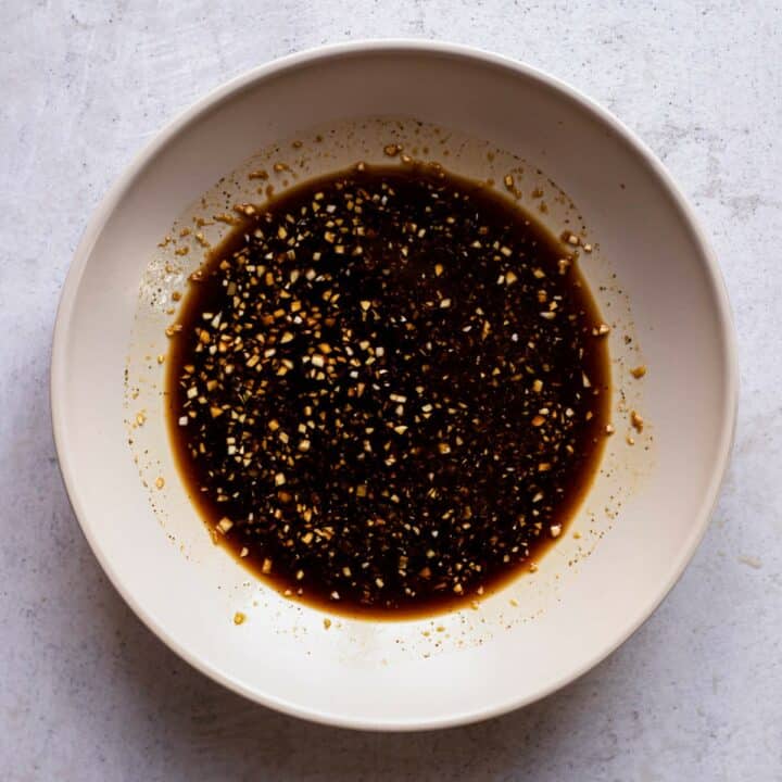 A bowl with soy sauce, honey, garlic, ginger and pepper mixed together.