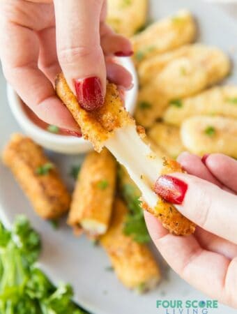 A mozzarella stick being pulled apart to show the melty cheese inside.