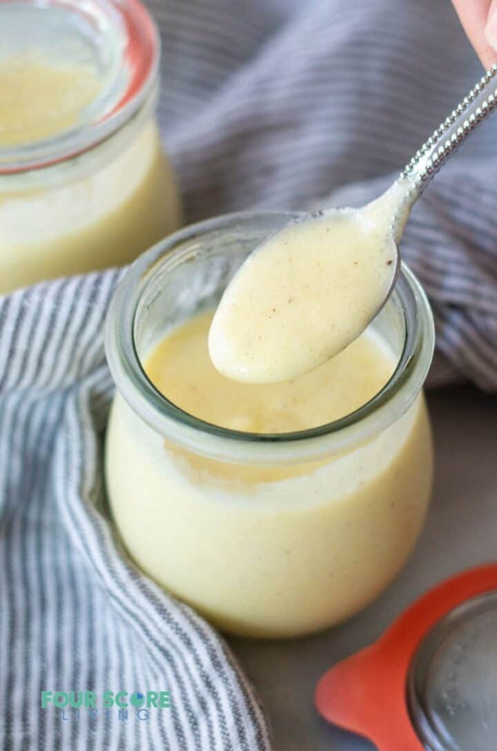 A spoonful of vanilla pudding over a jar of keto pudding.