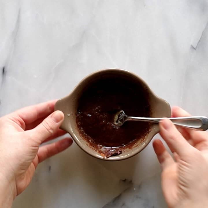 Keto chocolate mug cake batter in a bowl stirred with a spoon.