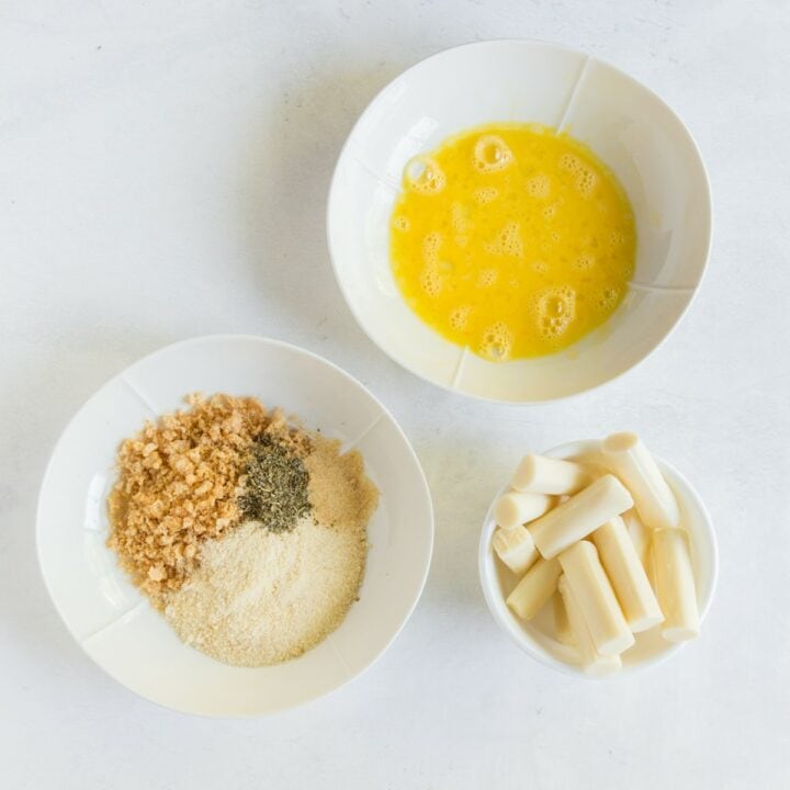 3 individual bowls. One with mozzarella sticks, one with egg wash and the other with the seasoned parmesan pork rind mixture.