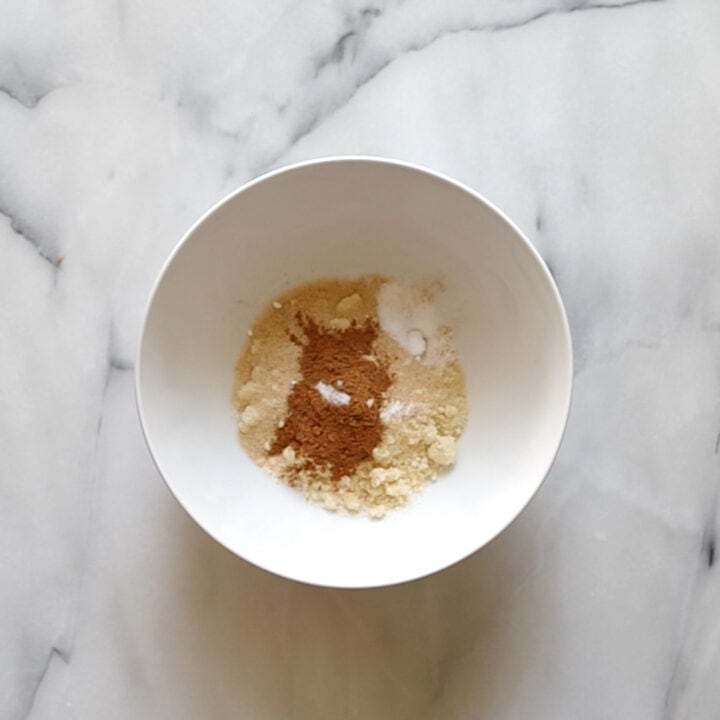 Medium sized bowl containing the dry ingredients, almond and coconut flour, pumpkin spice, salt, baking powder and sugar-free sweetener.