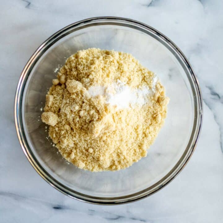 Glass mixing bowl with almond flour, salt, garlic powder and baking powder.