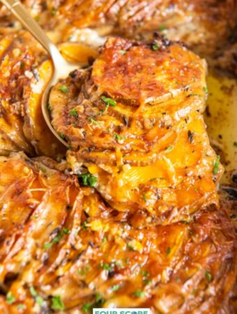 Scalloped sweet potatoes covered in melted cheese with a sprinkle of fresh green herbs being scooped with a serving utensil.