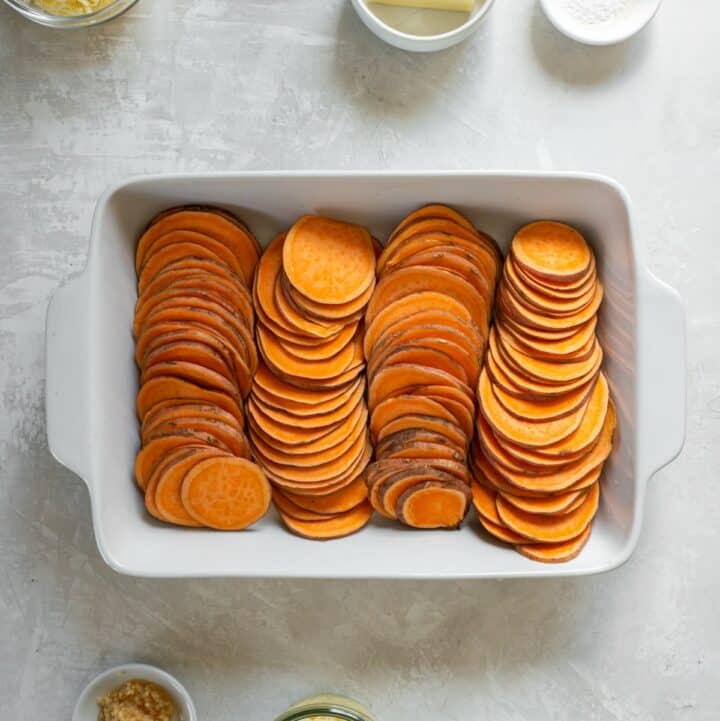 A baking dish with 4 rows of thinly sliced sweet potato rounds.