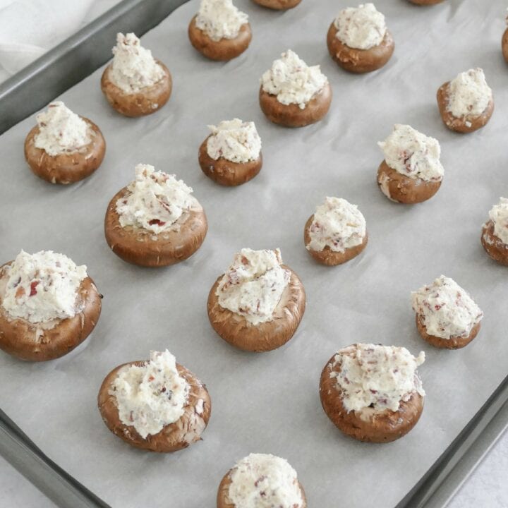 Filled keto stuffed mushrooms on a baking sheet ready to be placed into the oven.