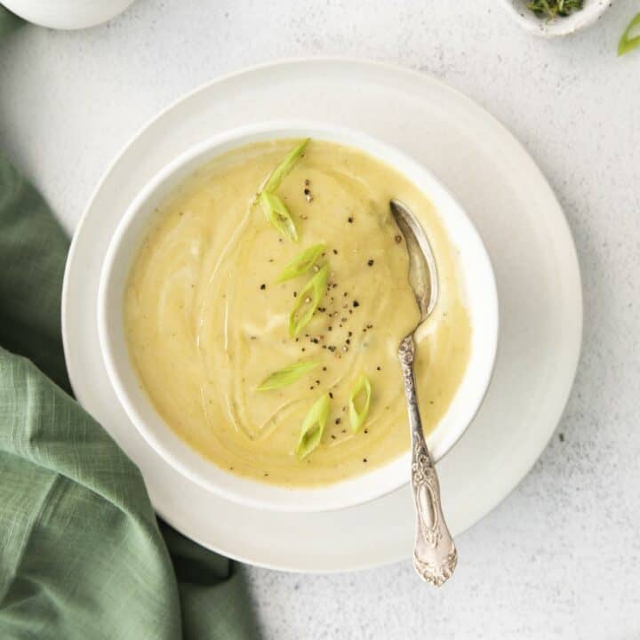 A bowl with magic leek soup, garnished with sliced green onions and fresh cracked black pepper.