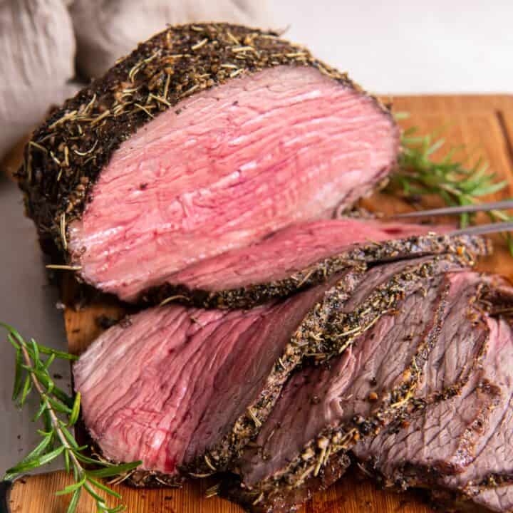 A juicy and tender beef bottom round roast carved on a wooden cutting board.