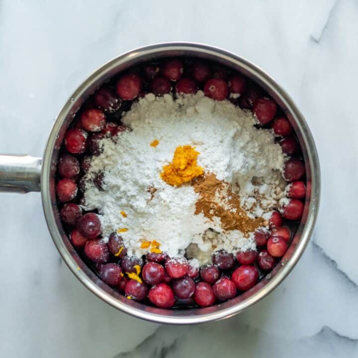 A small pot filled with all of the ingredients for making keto cranberry sauce.