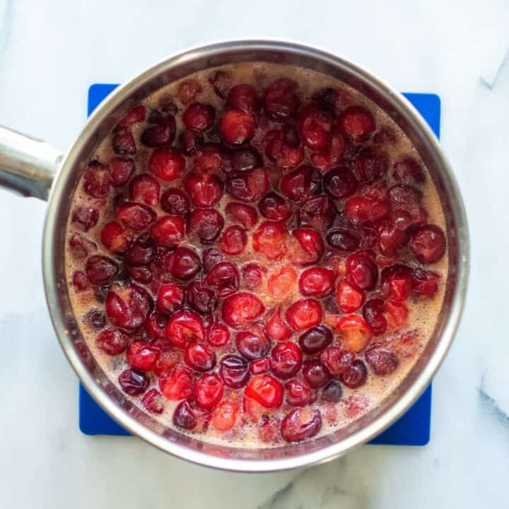 A small pot with cooked cranberries and other sauce ingredients.