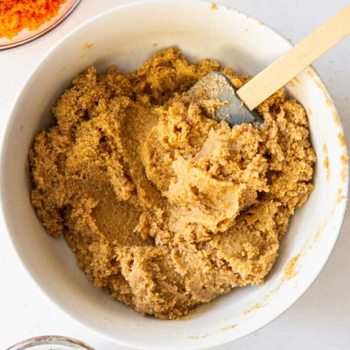 A bowl with the dry ingredients and wet ingredients being mixed together with a spatula.