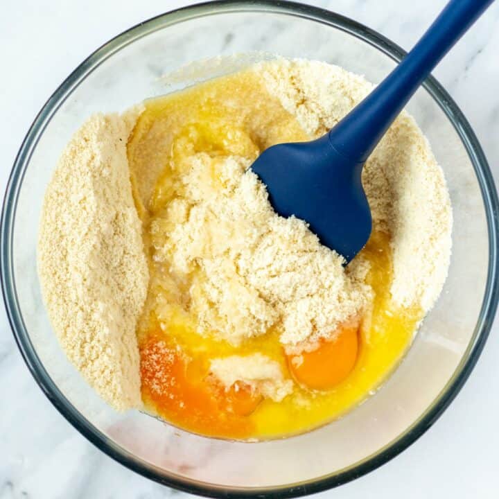 Glass bowl with the eggs and melted butter being added to the dry ingredients.