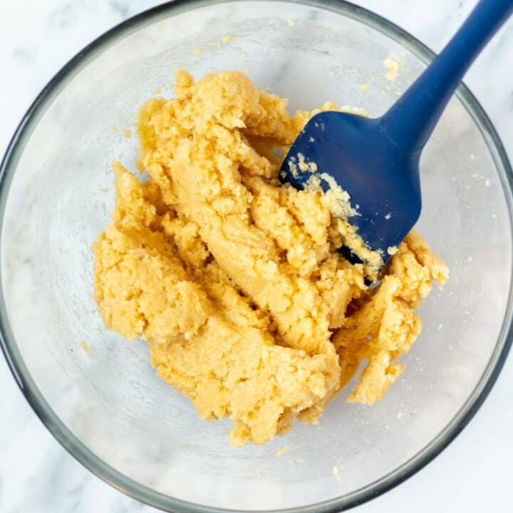 Glass bowl with the biscuits dough being mixed together with a spatula.