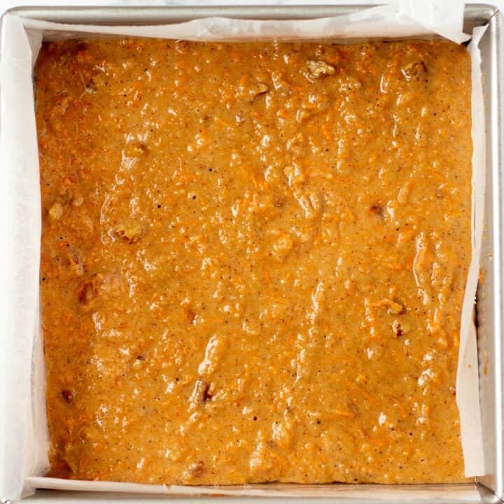 Carrot cake bars batter in a parchment lined 8*8 baking pan.