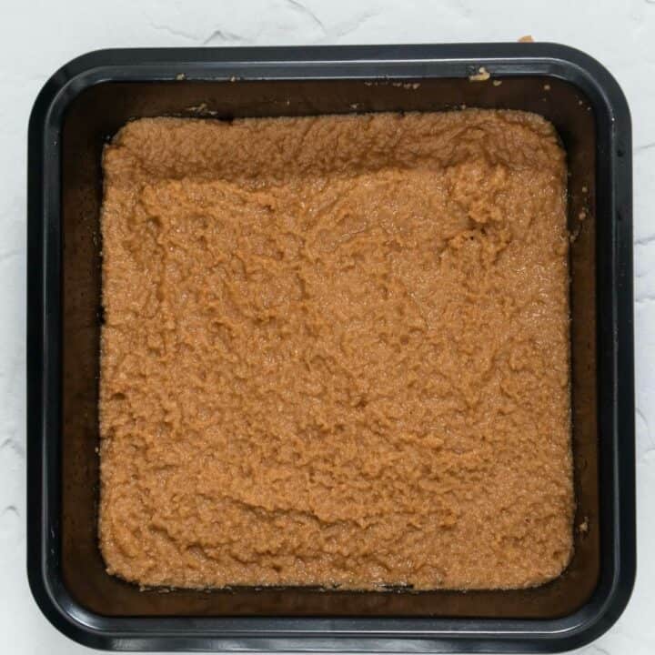 A square cake pan partially filled with keto coffee cake batter.