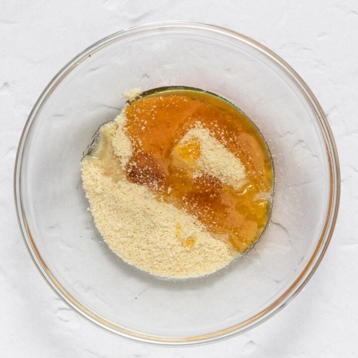 A glass bowl with the ingredients for making the crumb topping. Almond flour, oil and granulated sweetener.