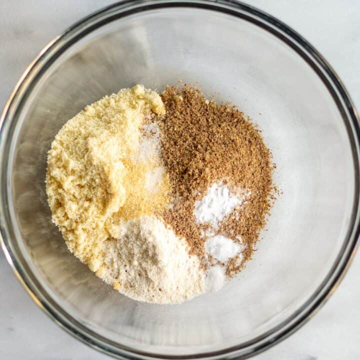 Glass bowl with all of the dry ingredients. Almond flour, flaxseed, coconut flour, baking soda and garlic powder.