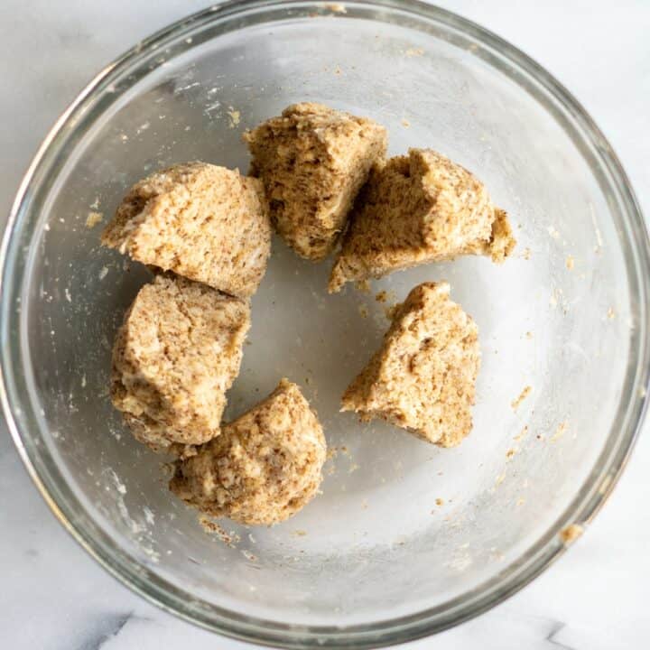 The kneaded dough cut into six equal pieces in a glass bowl.