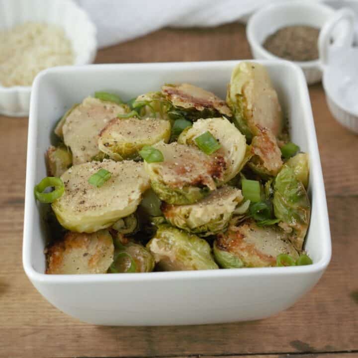 Golden brown Parmesan crusted Brussels sprouts in a square bowl ready to be served.