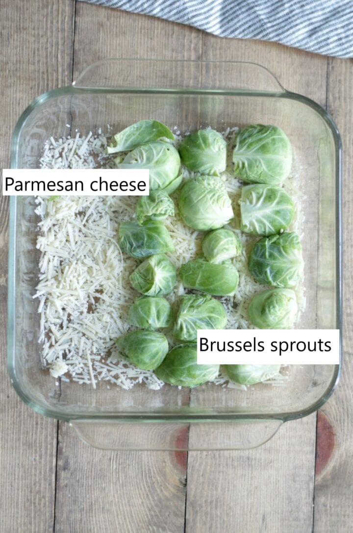 Glass baking dish with halved Brussels sprouts and grated parmesan cheese.