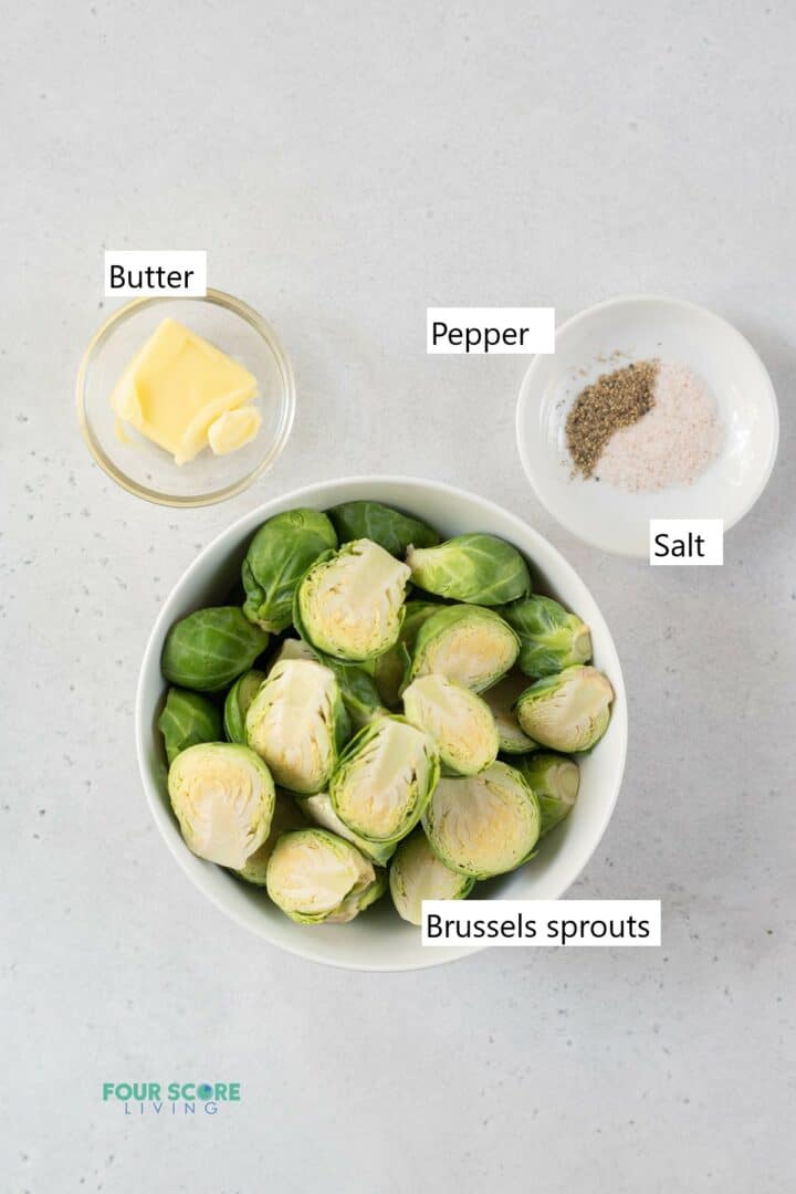 Ingredients to make steamed brussels sprouts in separate bowls, including brussels sprouts, butter, salt, and pepper.